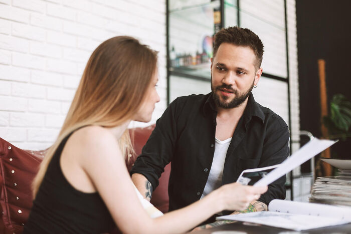 Conversation between man and woman reviewing documents in a modern office space.