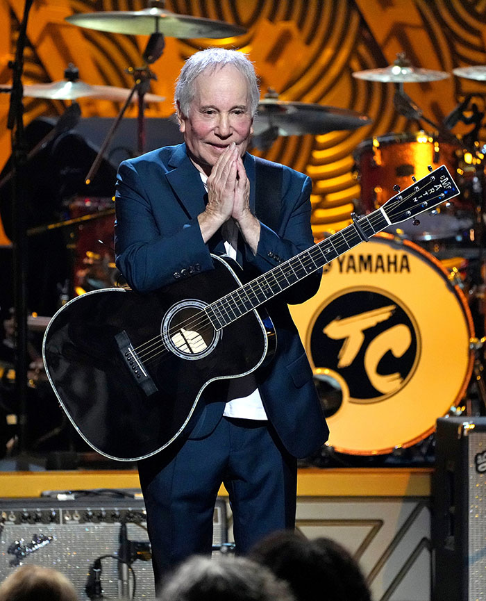 Paul Simon playing guitar on stage during a live performance, related to Richard Gere&rsquo;s multimillion-dollar home outcry.