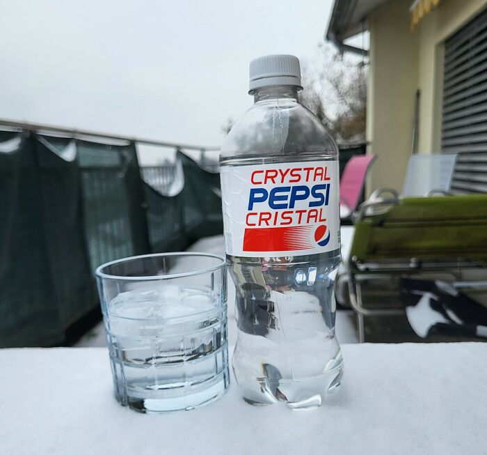 Clear Crystal Pepsi bottle next to a glass filled with ice on an outdoor table, representing the next big thing that totally flopped.