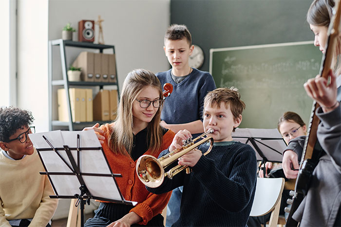 Group of diverse kids playing musical instruments in a classroom, capturing a moment of joy and confidence after overcoming a bully.