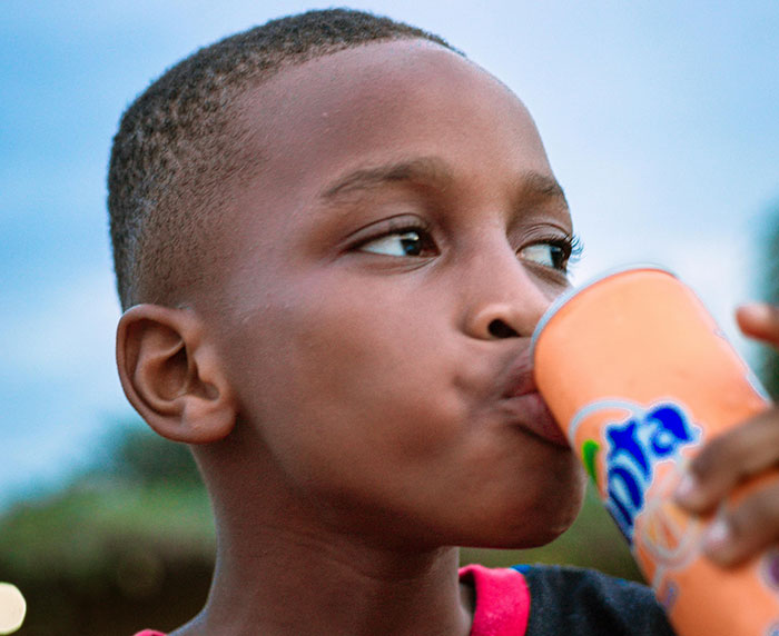 Young boy drinking from an orange soda can, capturing a moment related to getting even with a bully.