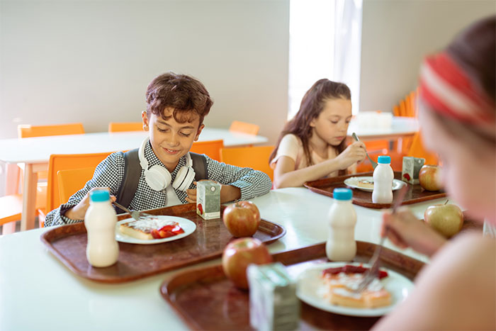Boy with headphones smiling during school lunch, sharing a moment of joy after standing up to a bully in cafeteria setting.