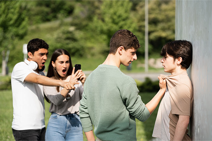 Teen boy confronting a bully while friends record and react, capturing a moment of finally getting even with a bully.