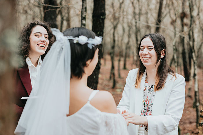 Three women smiling and holding hands during a joyful outdoor moment about getting even with a bully celebration.