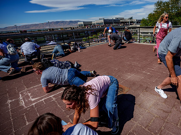 Bearded man in crowd during Charlie Kirk's attack spotted cheering and looking back amid chaotic scene on rooftop.
