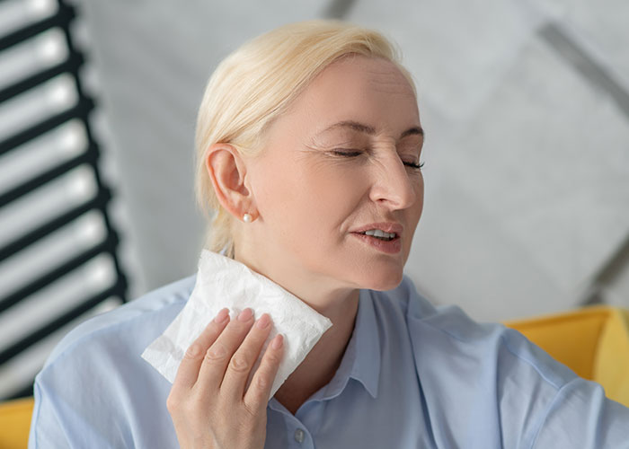 Middle-aged woman using a cool compress on her neck, illustrating life hacks that actually work at home.