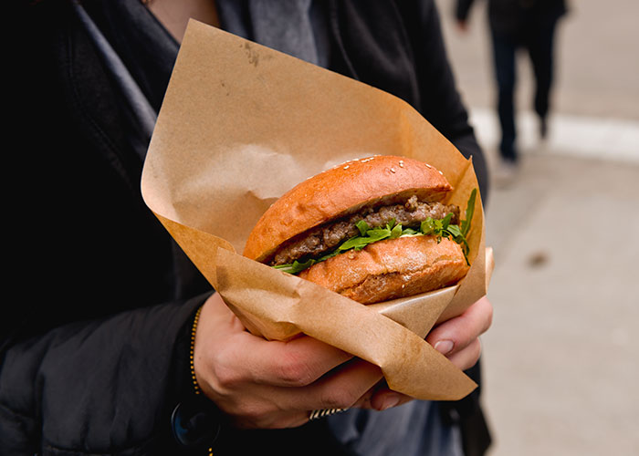 Person holding a wrapped burger showcasing a popular life hack for food preparation that actually works.