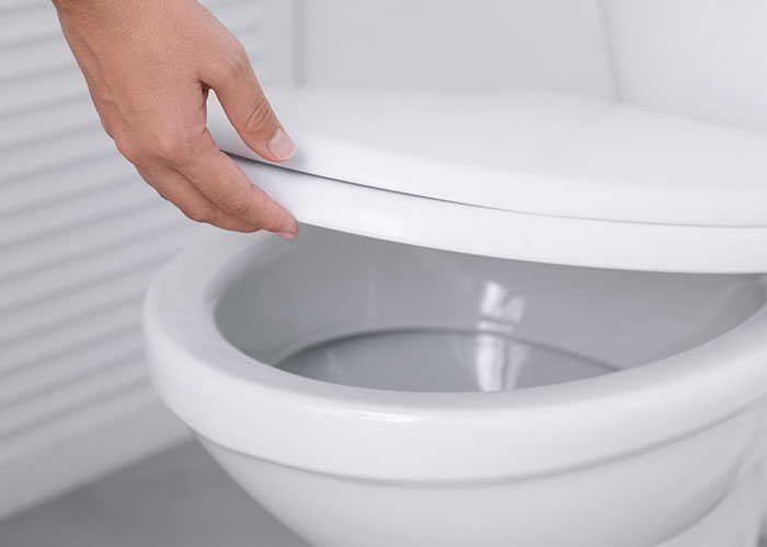 Hand lifting toilet seat lid, demonstrating a practical life hack that actually works for home improvement.