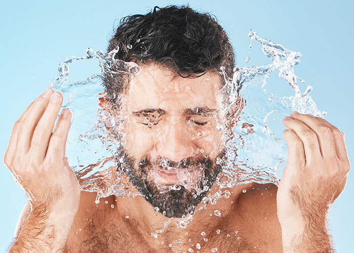 Man splashing water on his face with eyes closed, illustrating effective life hacks that actually work for daily routines.