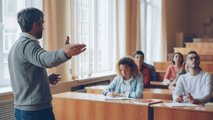 Teacher engaging students with funny jokes and iconic comments during a lively classroom discussion session.