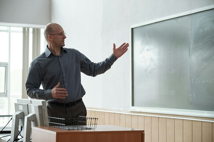 Teacher in a classroom giving a lesson while surprising students with funny jokes and iconic comments.