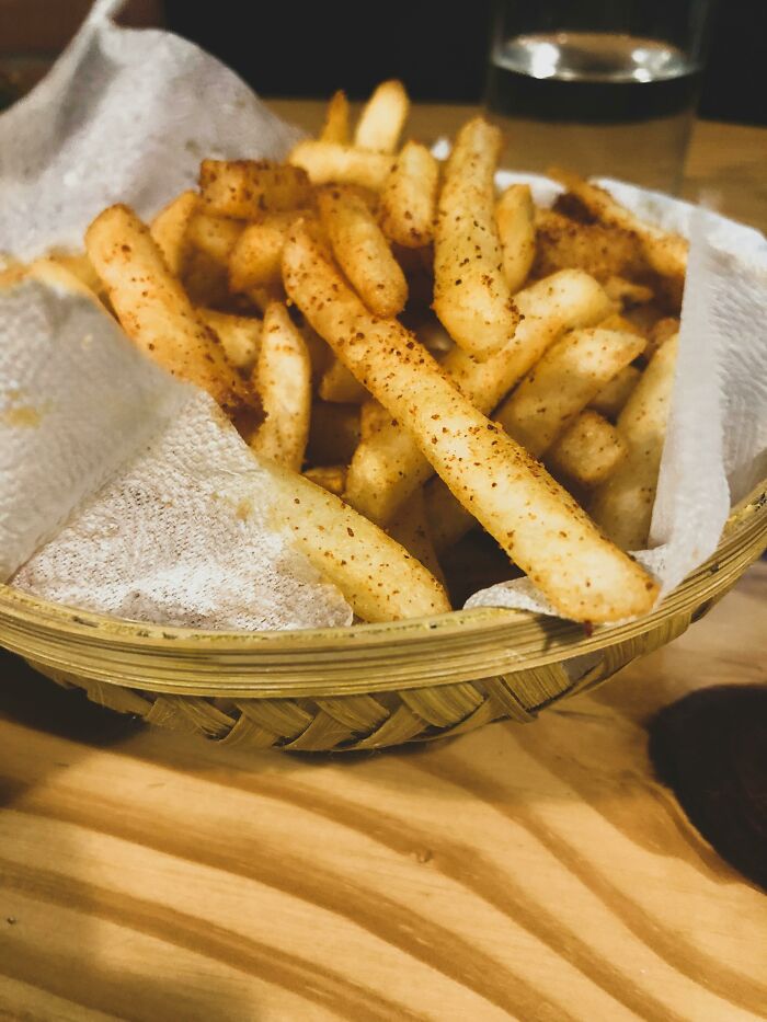Basket of seasoned fries on a wooden table, illustrating funny jokes and iconic comments shared by teachers.