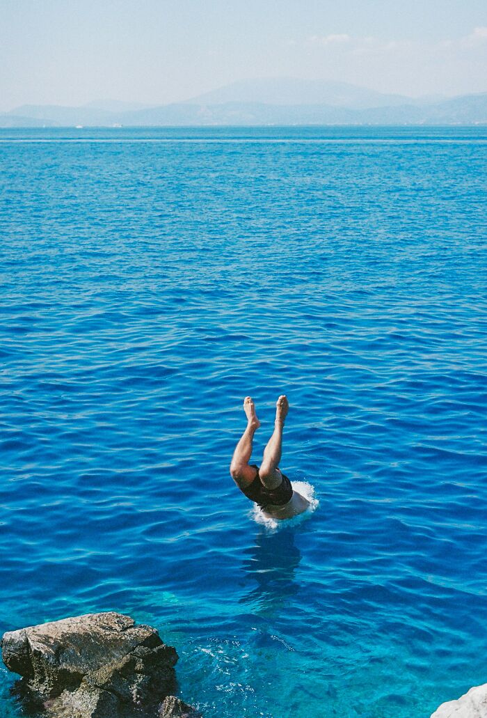 Person diving headfirst into the ocean near rocky cliffs, illustrating people who completely ruined their lives fast.