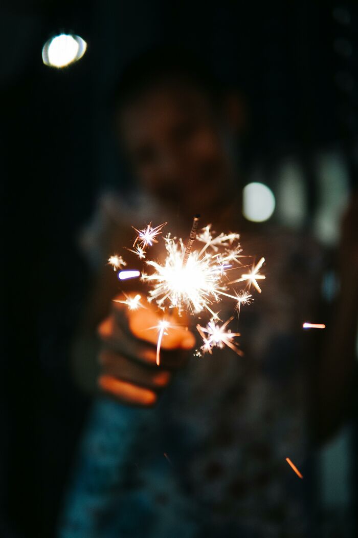 Person holding a lit sparkler in the dark, symbolizing people who completely ruined their lives quickly.