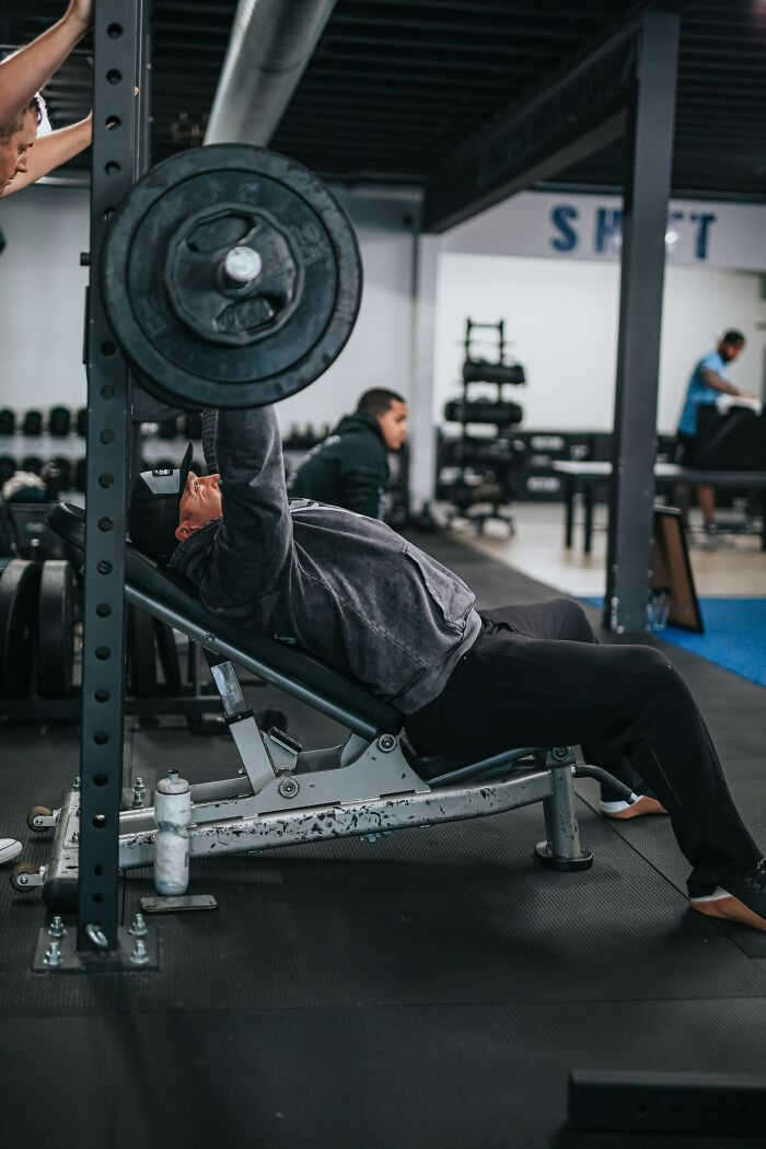 Man lifting weights on an incline bench in a gym, symbolizing strength to overcome corporate hell challenges.