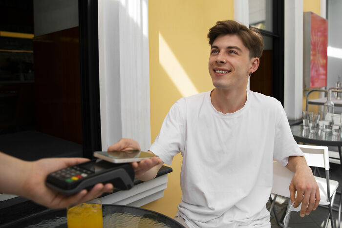 Young employee using contactless payment technology, sharing insider tricks to make jobs easier and more efficient.