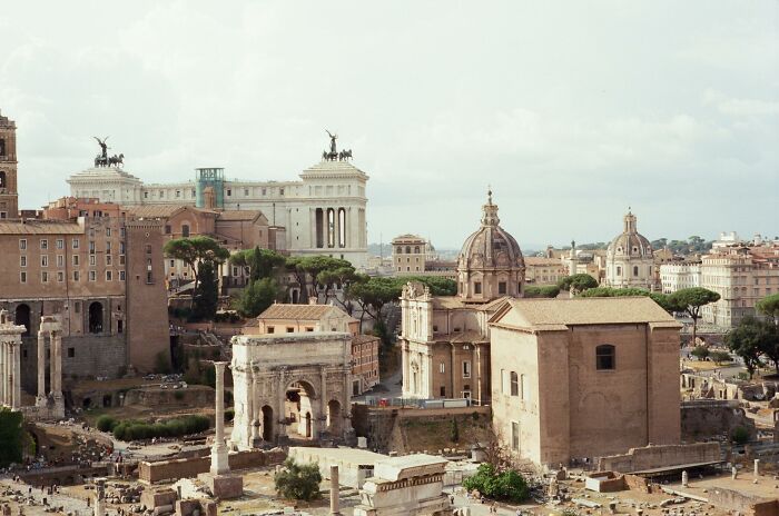 Ancient Roman ruins in Rome with historic buildings and clear sky, illustrating Roman idioms still used today.