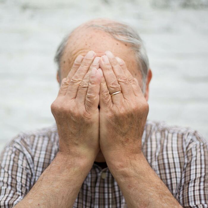 Elderly man covering face with hands, symbolizing a patient encountered by doctors with a rare disease.
