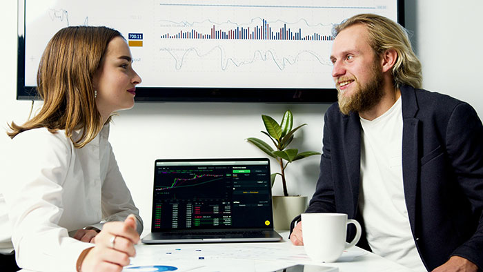 Two employees discussing financial data and paper trail in an office setting related to pet store manager fraud case.