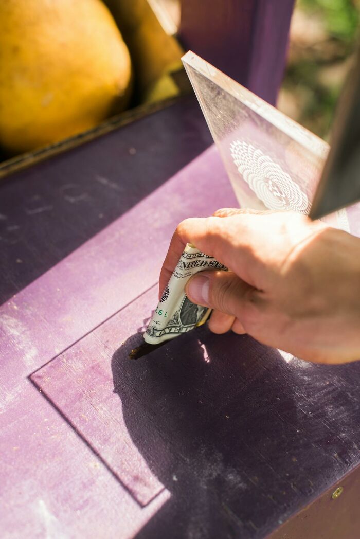 Hand placing a folded dollar bill into a slot, illustrating unique jobs for ultra-wealthy people.