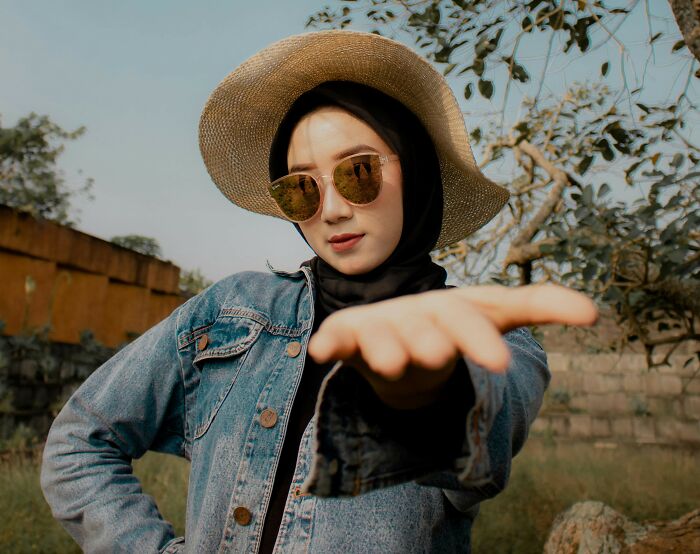Young woman wearing a straw hat and sunglasses outdoors, relating to men who married out of pressure life updates.