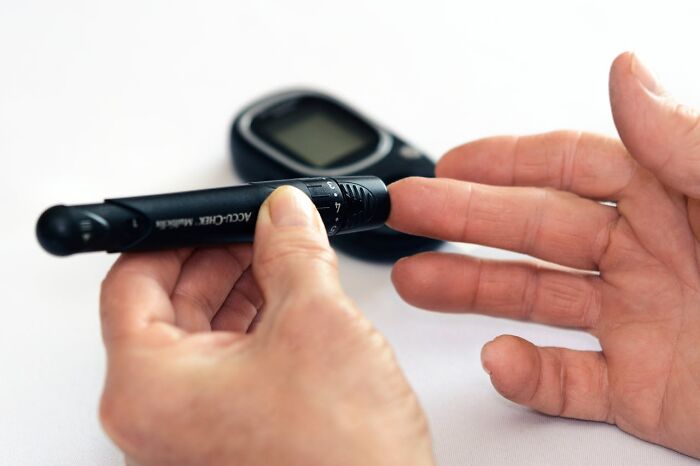 Person using a blood glucose meter to test blood sugar levels, highlighting rare disease patient care and monitoring.