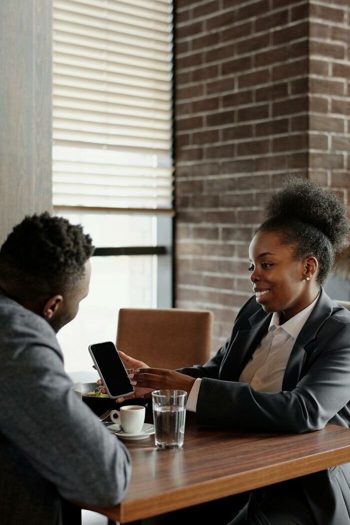 Two business professionals discussing at a cafe, highlighting moments of people fired for dumb workplace mistakes