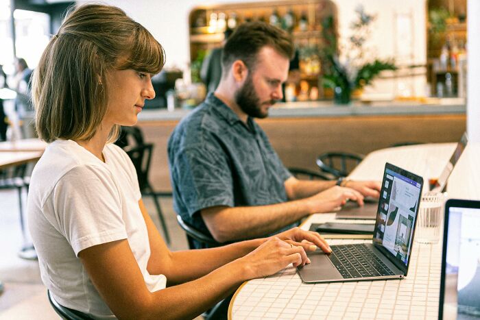 Young woman and man working on laptops in a cafe, illustrating sweet facade hiding manipulation and lies in real life.