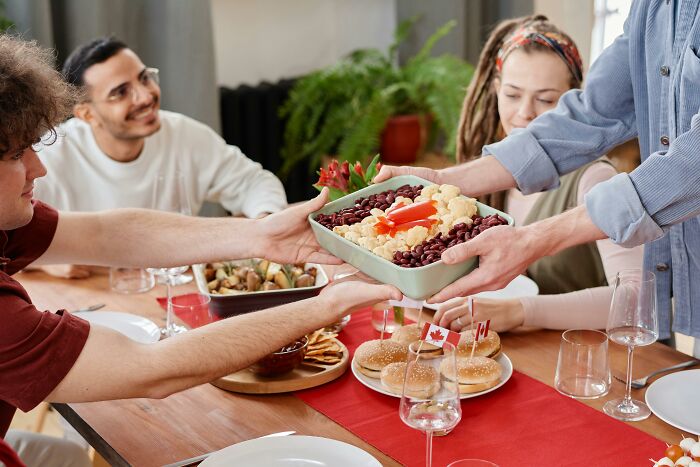 Group of friends sharing food at a table, showing sweet facade hiding manipulation or betrayal in real life.