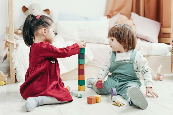 Two young children playing with colorful building blocks indoors, people share sounds extremely angry concept implied.