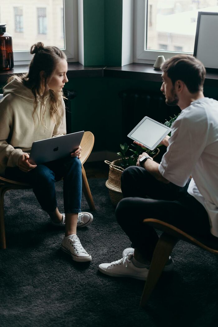 Woman and man sitting opposite each other indoors, discussing social issues about things women are not allowed to do freely.