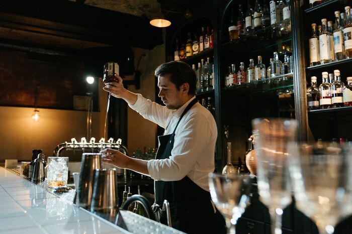 Bartender pouring a drink behind the bar, illustrating work mistakes that led to people getting fired.