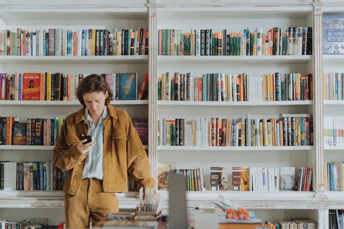Person in a bookstore looking at phone surrounded by shelves filled with books, capturing unbelievable things that were true.