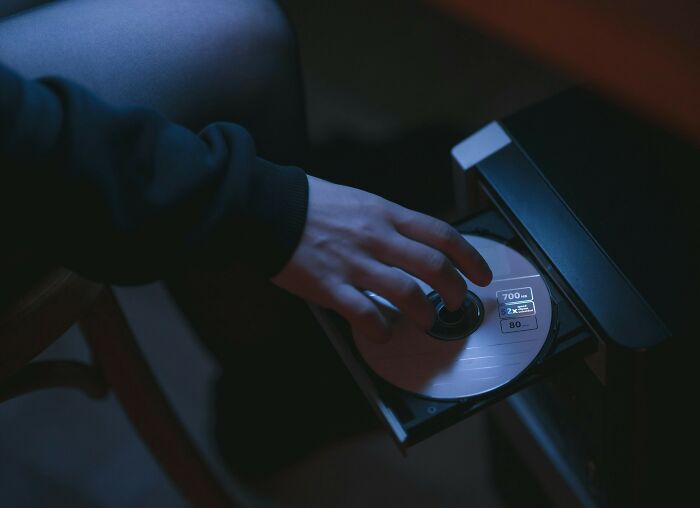 Person inserting a disc into a computer DVD drive, representing unexplained mysteries from the dawn of the internet.