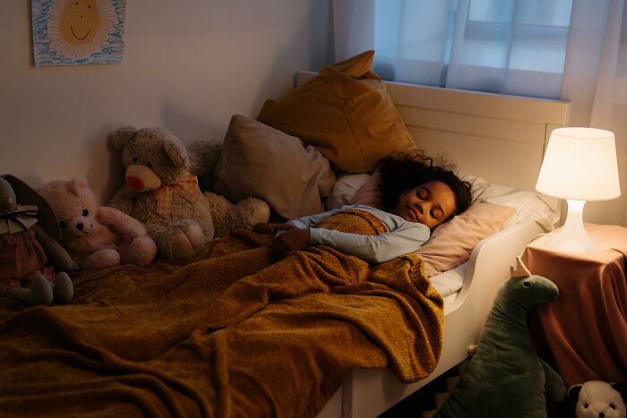 Child peacefully sleeping in bed surrounded by stuffed animals, illustrating parenting hacks that save sanity.