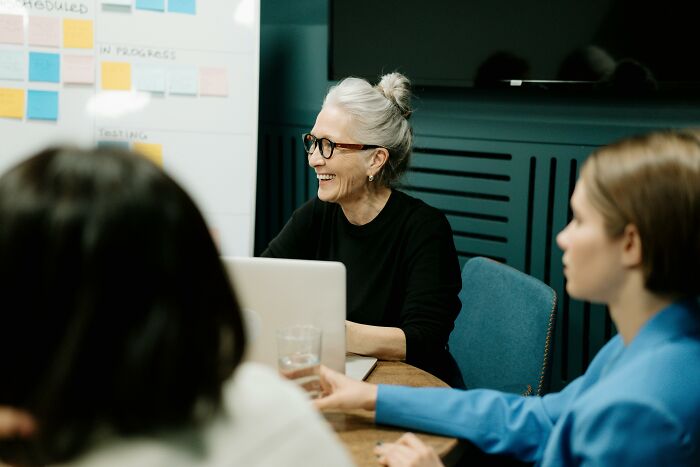 Women discussing subtle ways misogyny creeps into their daily lives during a professional meeting around a table.