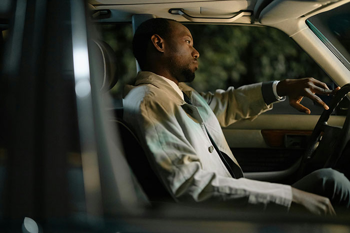 Man sitting inside car looking serious, illustrating entitled lady manipulating boyfriend and demanding free rides.