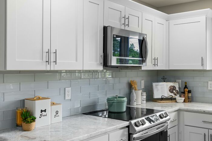 Modern kitchen with white cabinets and a stovetop, where people share sounds expressing extreme anger indoors.