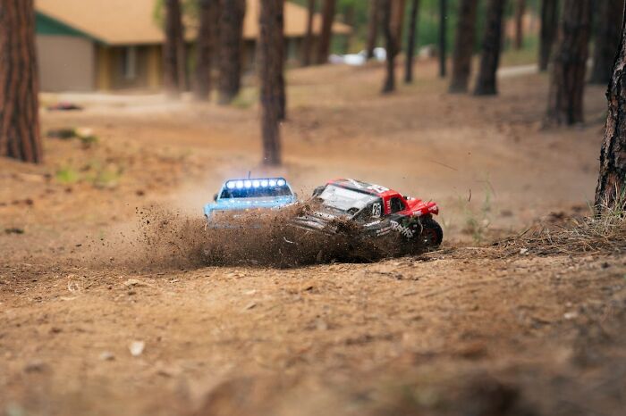 Two remote-controlled cars kicking up dirt in a forest, showing unbelievable moments that were actually true.