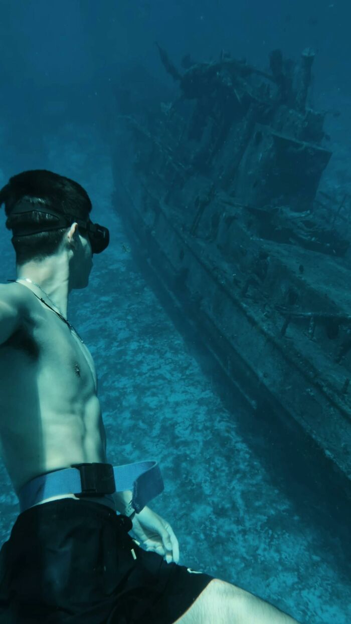 Underwater man exploring a sunken shipwreck, illustrating unusual jobs serving ultra-wealthy people.