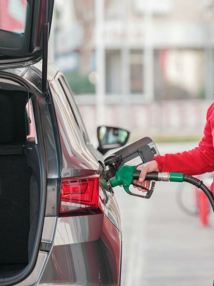 Person in red jacket filling car with fuel, illustrating unique jobs for ultra-wealthy people according to netizens.