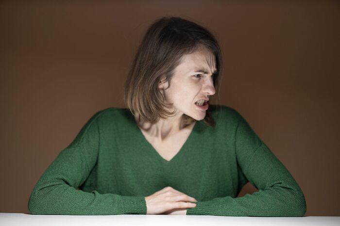 Young woman in a green sweater looking frustrated, illustrating moments people got fired due to their own mistakes.