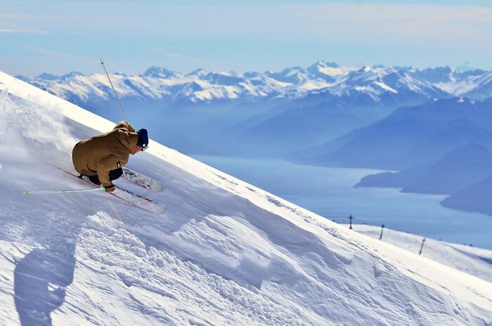 Skier descending a steep snowy mountain slope, capturing a moment that made them say they were definitely dead but survived without major injuries.