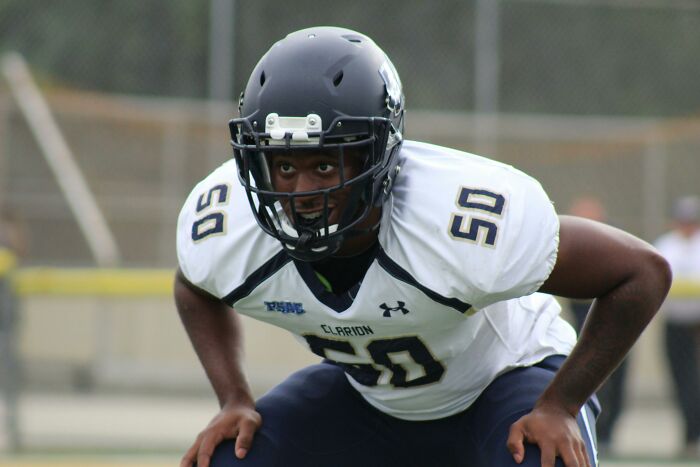 High school football player in helmet and jersey focusing intensely during a game, representing shocking school incidents.