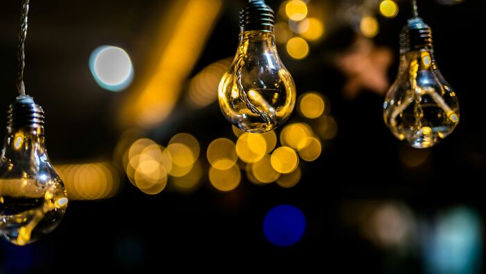 Close-up of glowing light bulbs with blurred warm yellow lights, evoking a mysterious atmosphere linked to hexes and witchcraft.