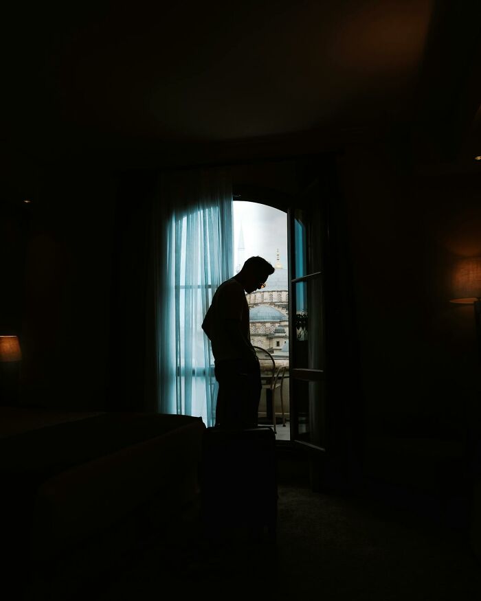 Silhouette of a person standing by a balcony door with an eerie atmosphere, perfect for creepy stories in dark woods.