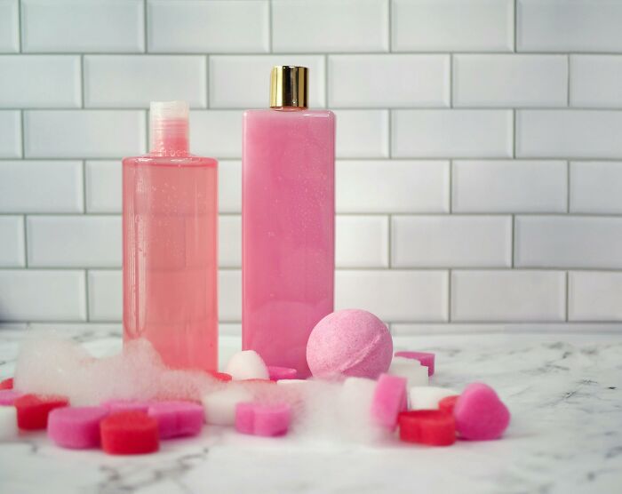 Pink bath products including bottles, bath bombs, and soap bars on a marble surface, illustrating overhyped products.