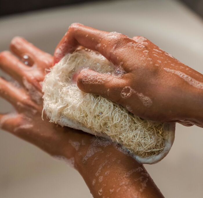 Hands scrubbing with a loofah sponge covered in soap bubbles symbolizing nasty things exes did shocking their partners.