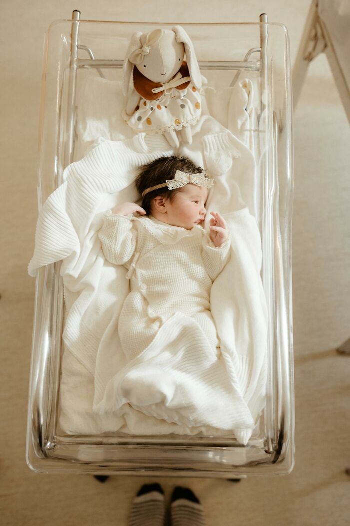 Newborn baby lying in hospital bassinet wrapped in white blankets with stuffed bunny, highlighting rare disease patient care.