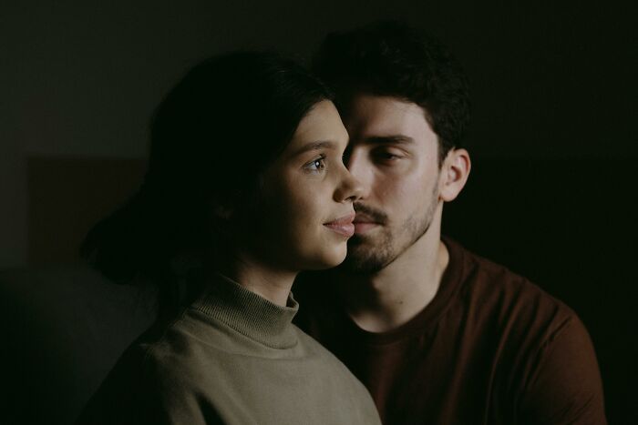 A thoughtful couple in dim light, reflecting on how to handle challenging scenarios with kindness and understanding.